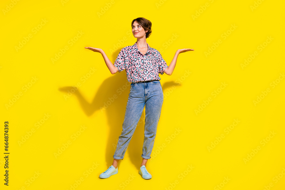 Full body photo of charming creative lady look arms hold empty space vs scales isolated on yellow color background Full body photo of charming creative lady look arms hold empty space vs scales isolated on yellow color background