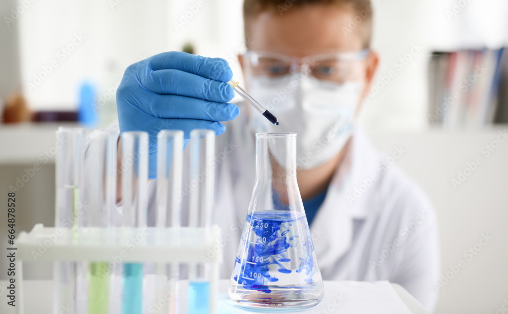 A male chemist holds test tube of glass in his hand overflows a liquid solution of potassium permanganate. Conducts an analysis of water samples versions of reagents using chemical manufacturing. A male chemist holds test tube of glass in his hand overflows a liquid solution of potassium permanganate. Conducts an analysis of water samples versions of reagents using chemical manufacturing.