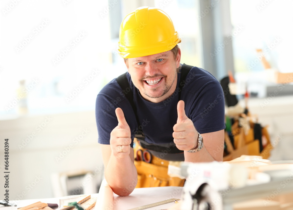 Smiling worker in yellow helmet show confirm sign with thumb up at arm portrait. Manual job DIY inspiration joinery startup idea fix shop hard hat industrial education profession career concept Smiling worker in yellow helmet show confirm sign with thumb up at arm portrait. Manual job DIY inspiration joinery startup idea fix shop hard hat industrial education profession career concept