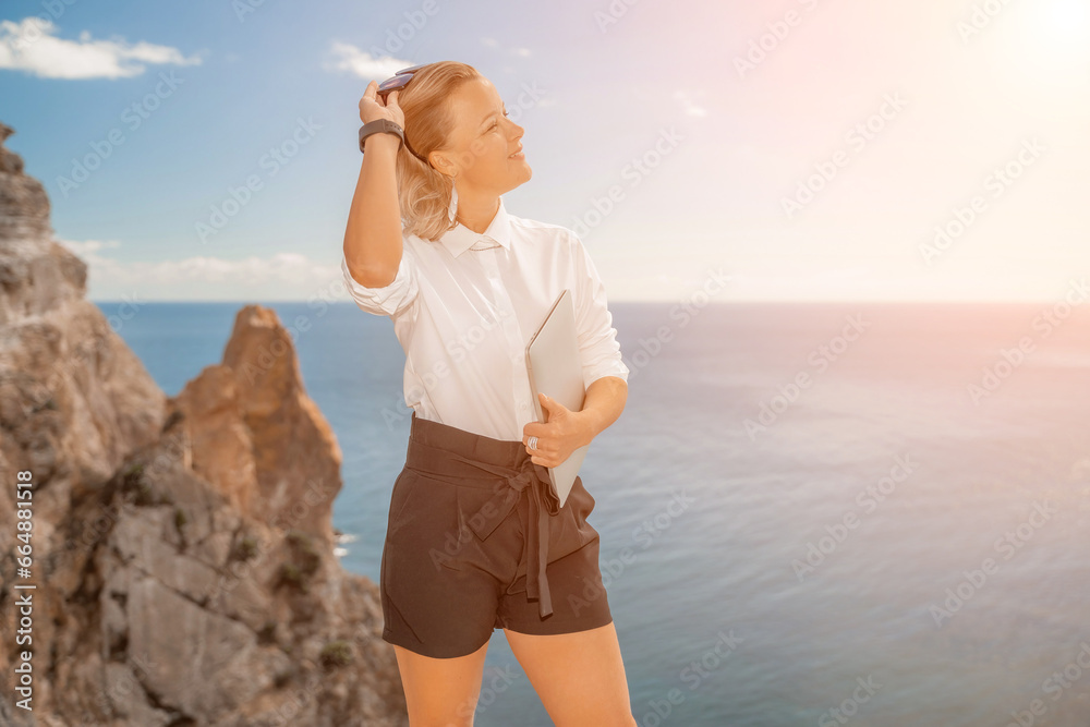 Freelance women sea working on a computer. Pretty middle aged woman with computer and phone outdoors with beautiful sea view. The concept of remote work. Freelance women sea working on a computer. Pretty middle aged woman with computer and phone outdoors with beautiful sea view. The concept of remote work.