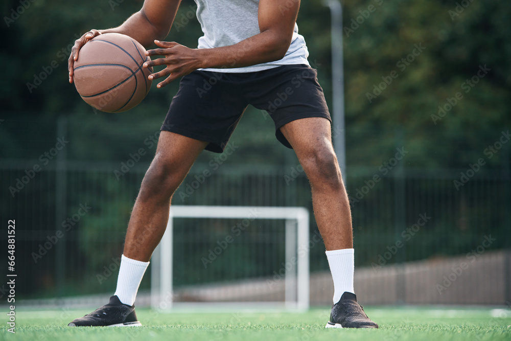 Fototapeta premium Close up view. Young black man is with basketball ball outdoors