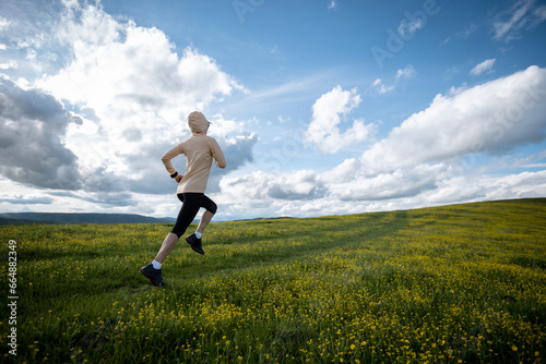 Woman trail runner cross country running at high altitude flowering mountain