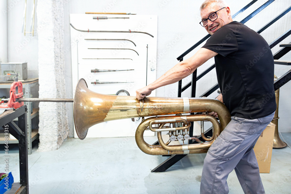 repair technician removing the bumps on the bell of a tuba in a brass