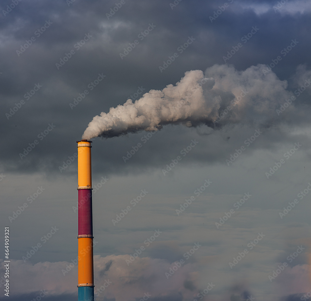 Smokestack against a moody sky. Factory chimney releasing emissions.