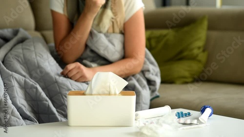 The woman uses a nasal spray. The woman takes a nasal spray, uses it, and puts it back on the table.