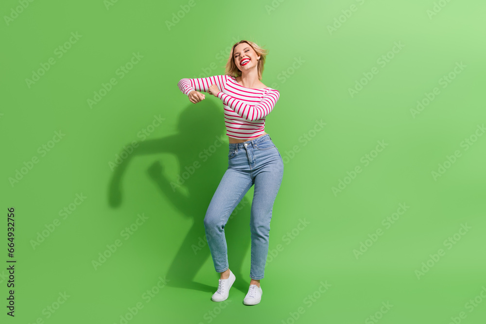 Full length photo of shiny cute girl dressed striped shirt dancing discotheque empty space isolated green color background