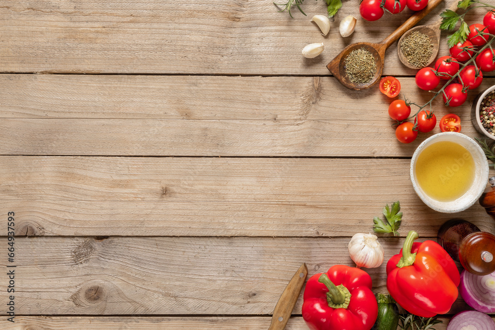 Healthy food cooking ingredients background with fresh vegetables, herbs, spices and olive oil on wooden table with copy space top view Healthy food cooking ingredients background with fresh vegetables, herbs, spices and olive oil on wooden table with copy space top view