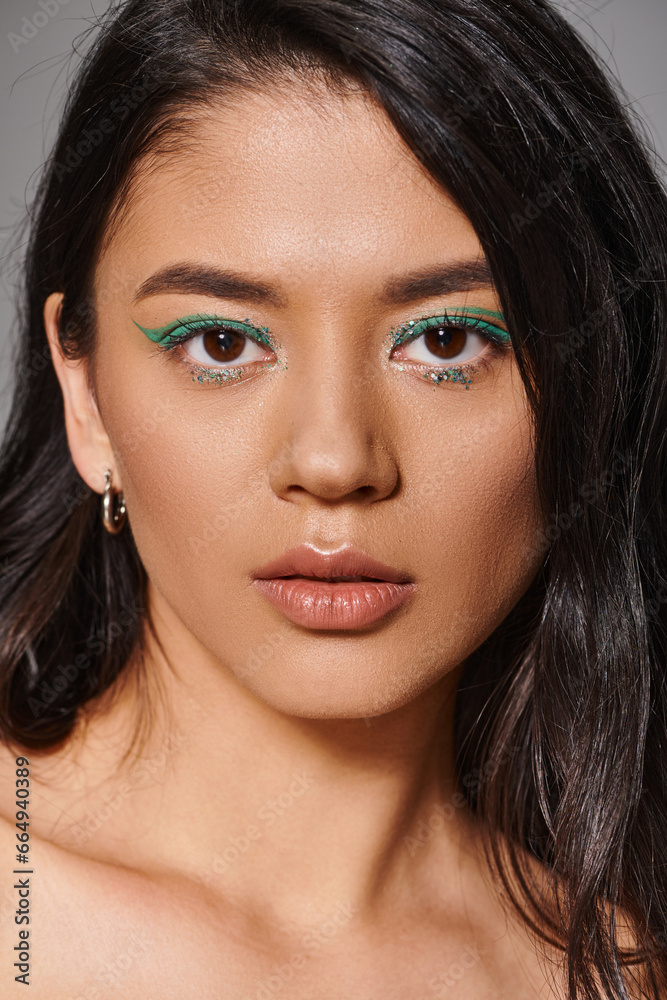 portrait of beautiful asian woman with brunette hair and shimmery eye makeup on grey background portrait of beautiful asian woman with brunette hair and shimmery eye makeup on grey background