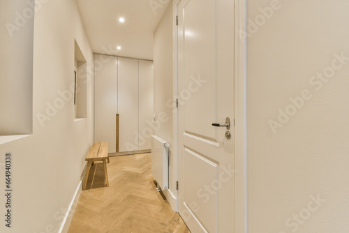 a long hallway with white walls and wood flooring on either side by side  leading to the other rooms