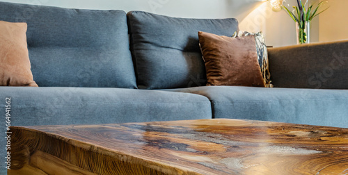 live edge wooden accent coffee table near sofa close up interior design of modern living roo  photo
