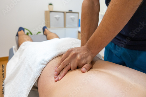 A hand is gently applying physiotherapy to a man’s back