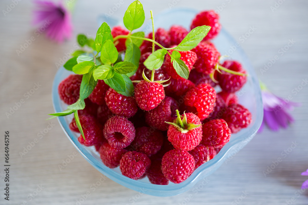 Fresh ripe raspberries in a glass bowl on wooden table. Fresh ripe raspberries in a glass bowl on wooden table.