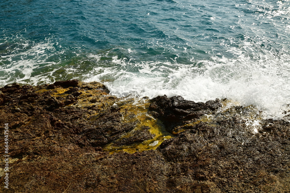 Waves hit rocks at shore Greek island of Kalymnos summer sun water