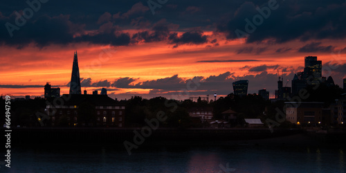 Panoramic picture of City of London view silhouette at the orange and red sky, view from the Thames river. Evening. (ID: 664947519)