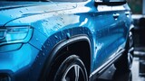 A blue compact SUV with a sporty, modern design is being washed with water, illustrating the concept of car care services.