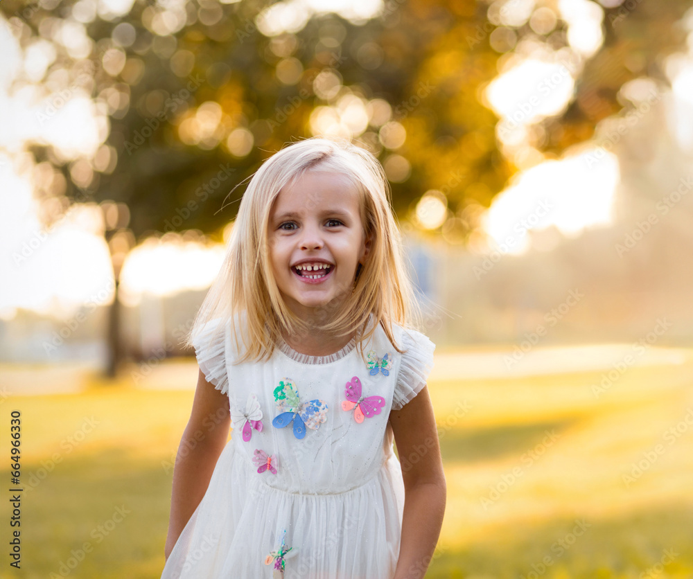 Portrait of a beautiful cheerful child girl on a sunny day in a city park at sunset, looking at the camera and smiling Portrait of a beautiful cheerful child girl on a sunny day in a city park at sunset, looking at the camera and smiling