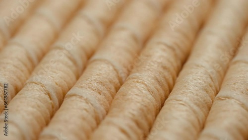 Blurry speedramp dolly shot, macro view of creamy wafer rolls lie in a row on conveyor belt, confectionery factory, production of sweet crispy pastries photo