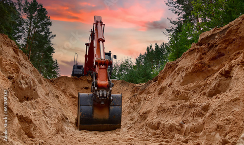 Excavator dig trench at forest area on amazing sunset background. Backgoe on earthwork for laying crude oil and natural gas pipeline or water main pipes. Construction the sewage and drainage
 photo