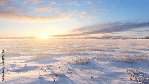 Snow-covered field at sunset with bright sun and clouds.