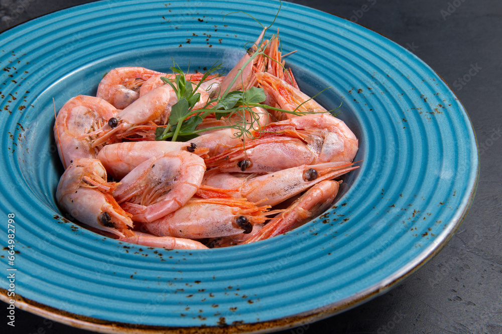 Cooked shrimp in a plate. On a dark background. Cooked shrimp in a plate. On a dark background.