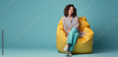 Happy young woman sitting in soft chair bag isolated on flat background with copy space, modern minimal style banner template.  photo