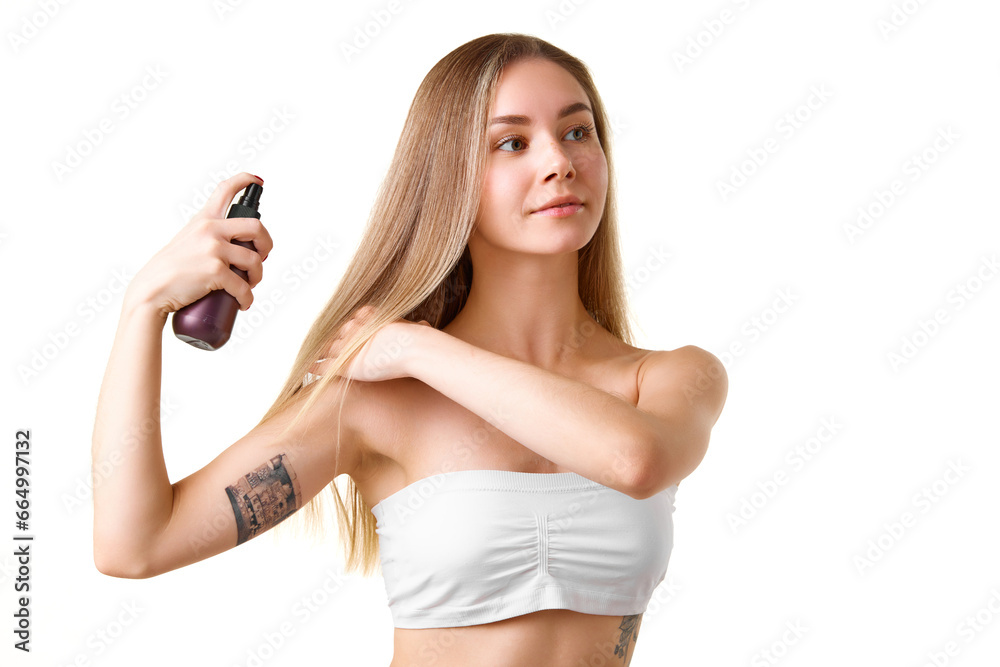 Pretty young girl taking care after blonde hair, sing spray and heat protection isolated over white studio background. Concept of natural beauty, skincare, cosmetics and cosmetology Pretty young girl taking care after blonde hair, sing spray and heat protection isolated over white studio background. Concept of natural beauty, skincare, cosmetics and cosmetology