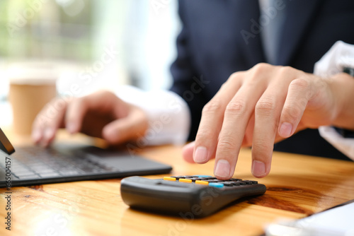 Businessman's hands working with calculator and laptop.