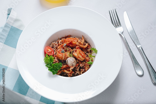 buckwheat with seafood, oyster, tomato and herbs in a deep plate side view