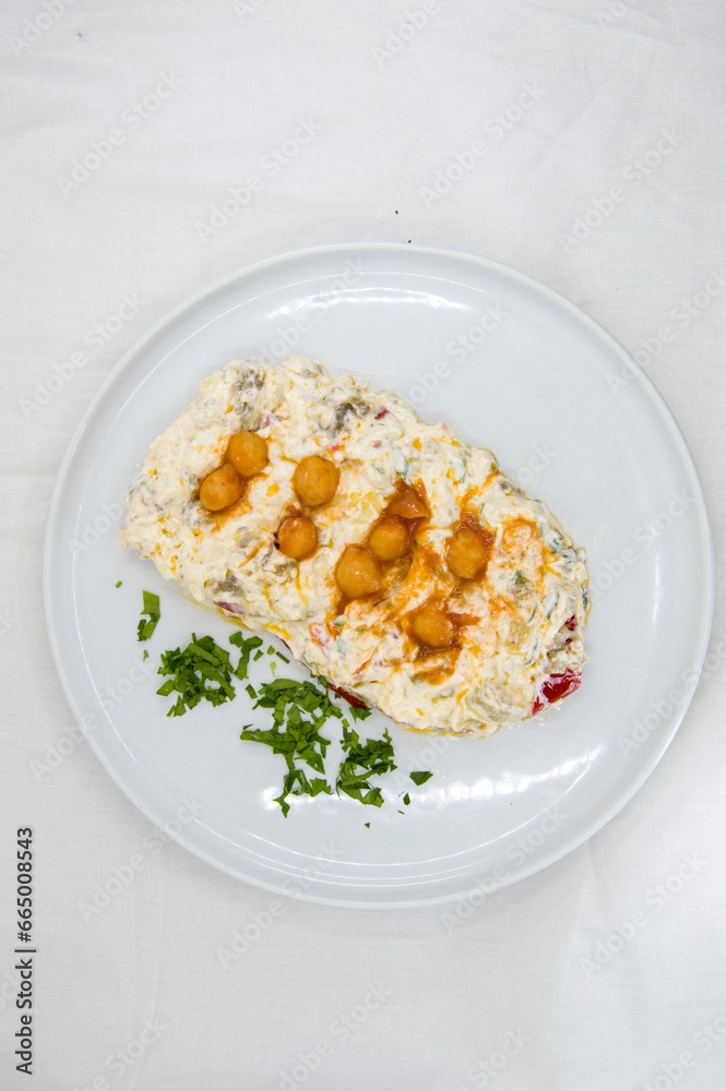 Carrot paste with yoghurt and chickpeas for decoration, served on a white plate