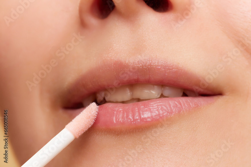 Cropped close-up image of young girl taking car after lips  applying moisturizing lip balm  oil. Concept of natural beauty  skincare  cosmetics and cosmetology