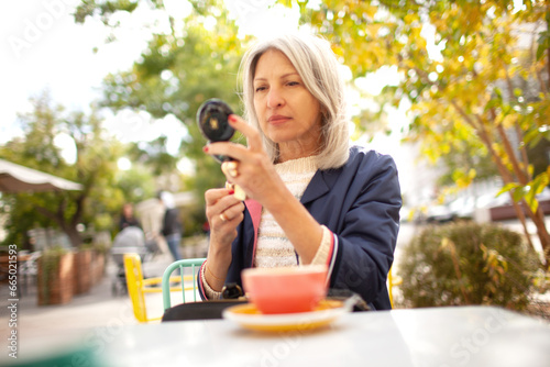 A  beauttiful woman with grey hair iun cafe. A stylish woman is wearing a jeans, blue jacket and a bag photo