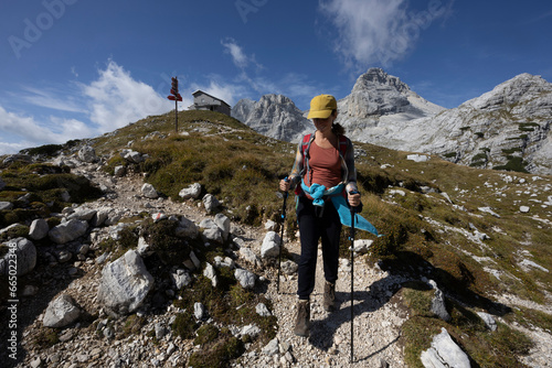 Woman Hiking Solo from a starting point with mountain hut in Alps 