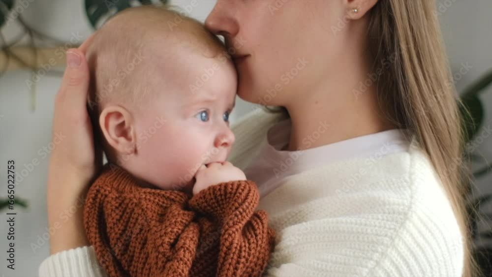 Caring mom embrace caress lull little toddler son. Close-up portrait of loving young mother holding in arms hug cuddle cute baby boy child standing in living room with home plants. Motherhood concept