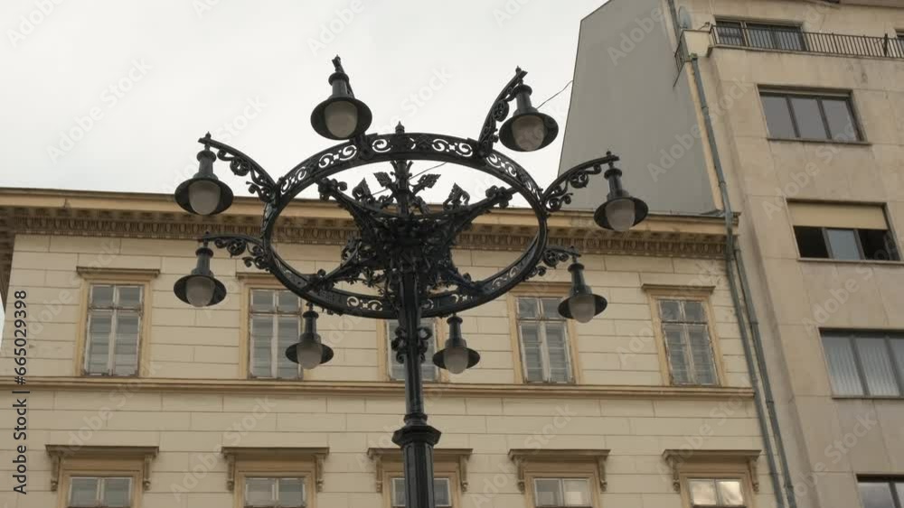 Black retro street lamp during day city. A view of black street lamp in retro style against buildings facade. Black retro street lamp during day city. A view of black street lamp in retro style against buildings facade.