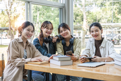Group of cheerful Asian college students or friends laughing together while sitting in university.