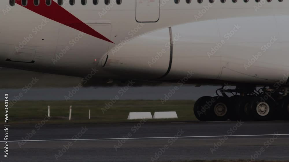 Close-up of a widebody jet taxiing on the airport runway, with its landing gear turning around on the tarmac Close-up of a widebody jet taxiing on the airport runway, with its landing gear turning around on the tarmac