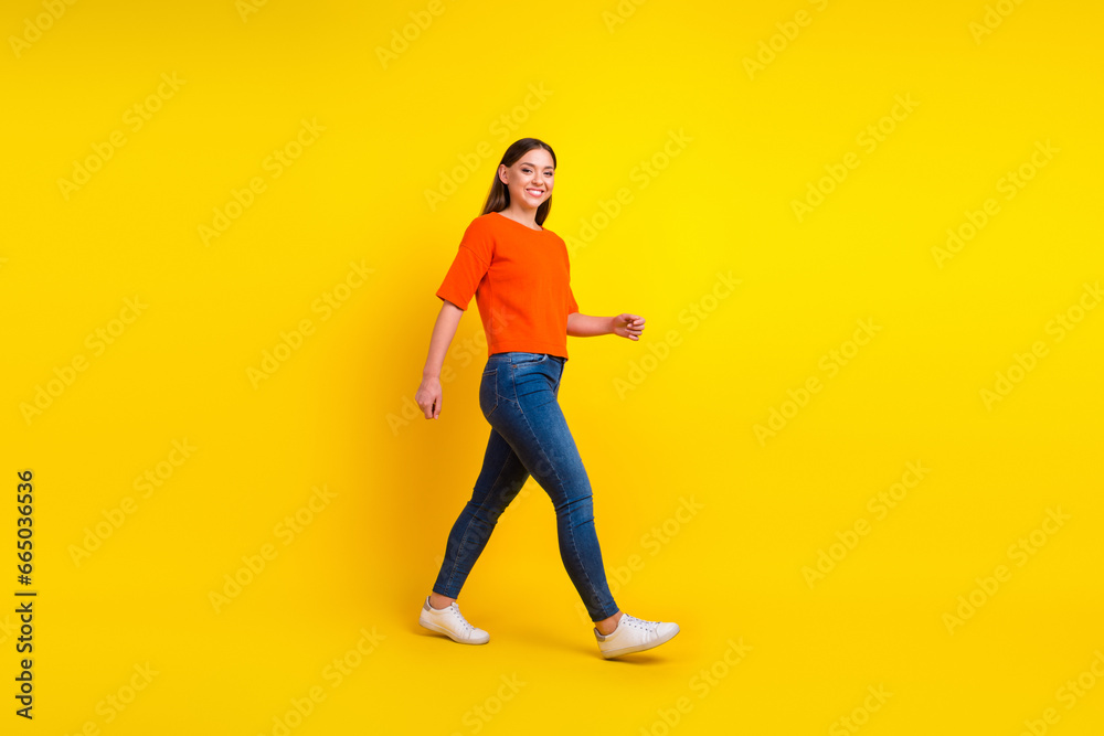 Full size body length side view profile excited young brunette woman walk go move stroll isolated on yellow background