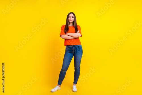 Full length photo of young beautiful woman stand with crossed hands on isolated yellow background