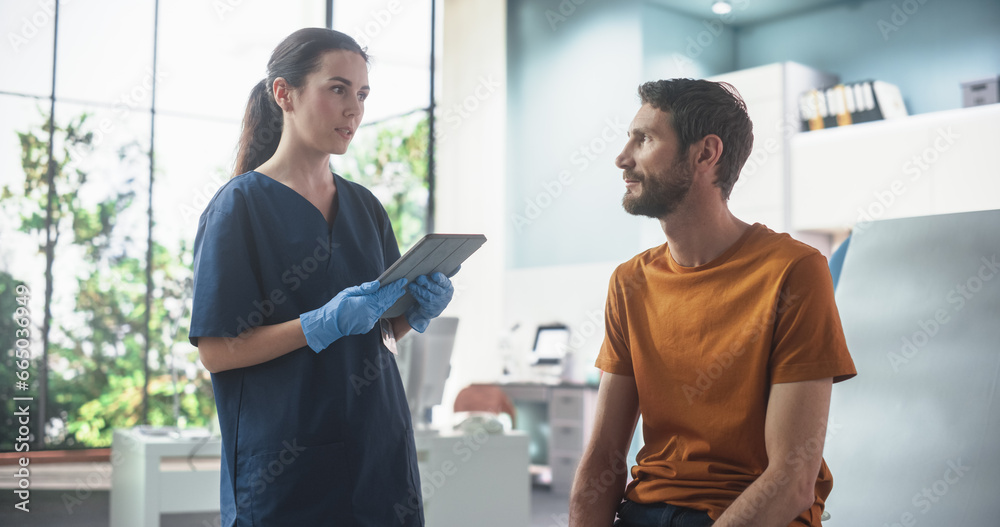 Fototapeta premium Caucasian Man Sitting In The Chair In Bright Hospital And Listening To Female Nurse With Tablet Computer. Professional Woman Explaining Possible Side Effects After Vaccination Or Medicine Injection.