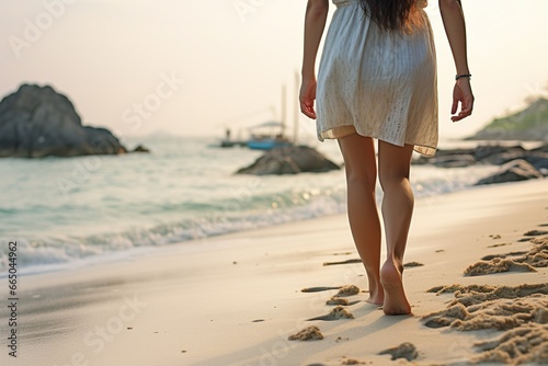 Closeup of female bare feet in long skirt walking on the sandy sea beach at sunset © Wall Art Galerie