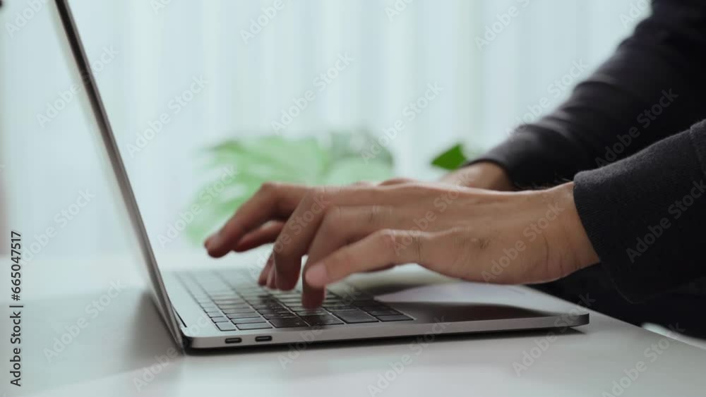 The man's hand is typing on a laptop computer keyboard at home or in the office. He is working, sending messages, chatting, browsing the internet, and using social networking. The man's hand is typing on a laptop computer keyboard at home or in the office. He is working, sending messages, chatting, browsing the internet, and using social networking.