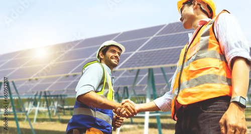 Fotografie Caucasian male architect and Asian engineer electrician shaking hands working colleagues team believing positive approach planning solar power project solar panels success developing energy industry