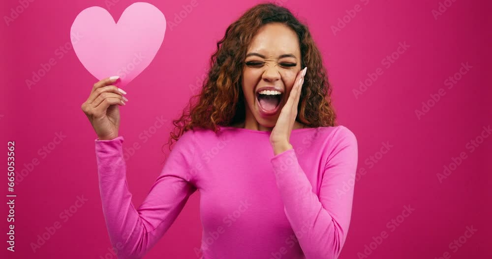 Surprised young woman finds love, shocked face looking at heart, studio Surprised young woman finds love, shocked face looking at heart, studio
