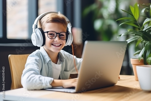 Smiling little boy in headphones have video call distant class with teacher using laptop