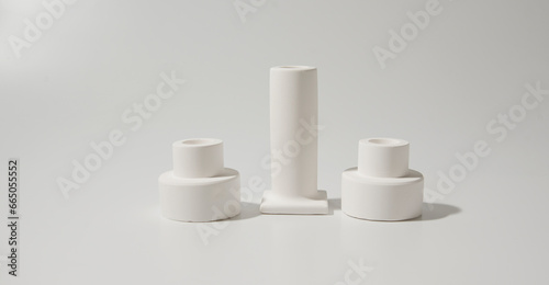 White ceramic candles stand on white background. interior concept