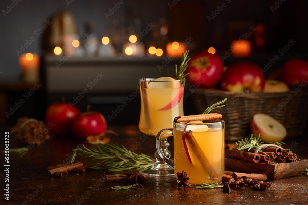 Mulled cider with apples, cinnamon, rosemary, and anise on a background of burning candles. Mulled cider with apples, cinnamon, rosemary, and anise on a background of burning candles.