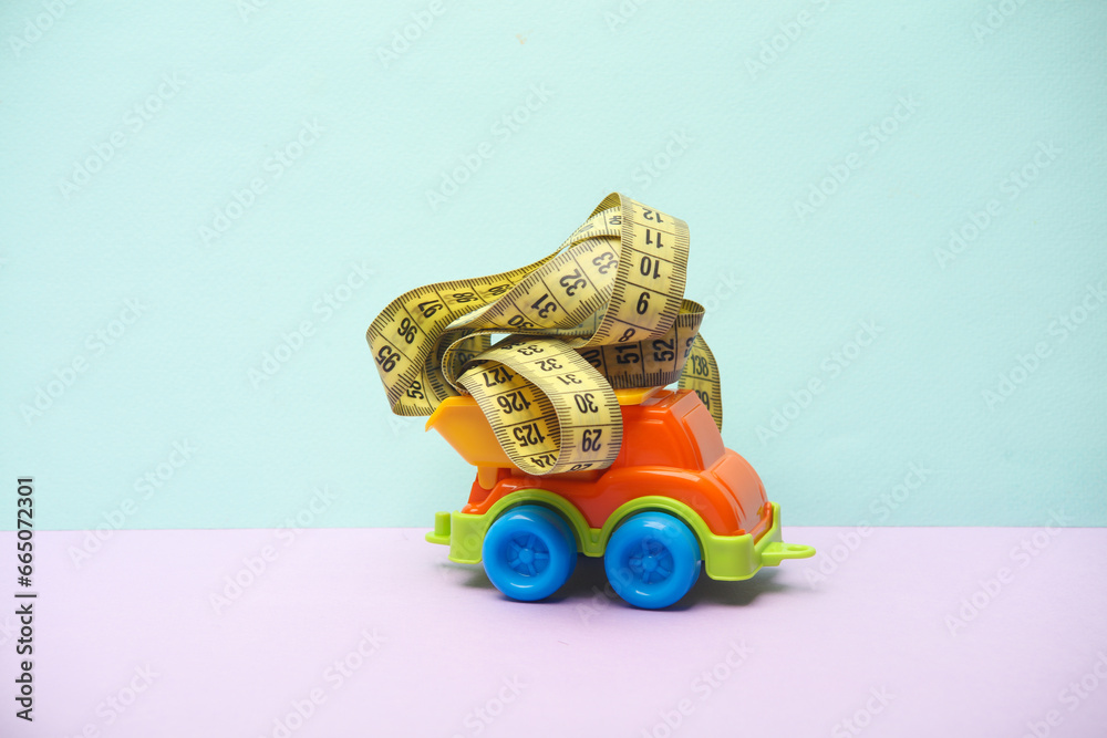 Toy dump truck with measure tape on a pastel background Toy dump truck with measure tape on a pastel background