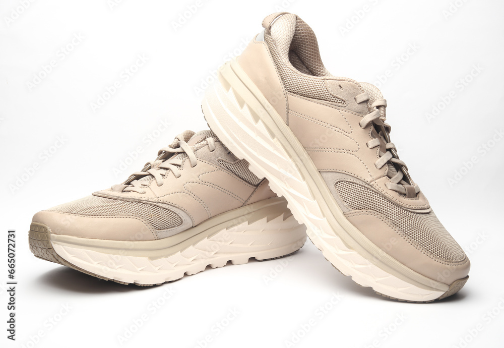Pair of beige leather running shoes isolated on white background