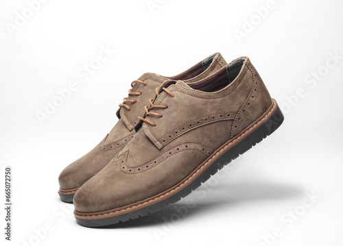 Pair of levitating leather brogue shoes on a white background