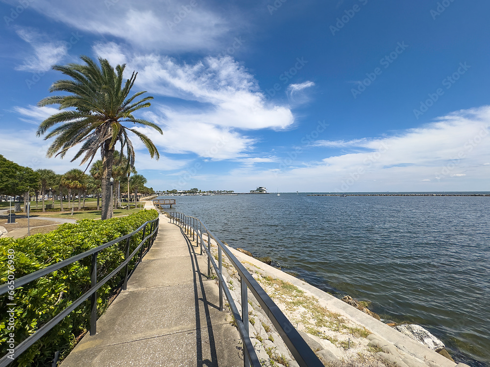 Perspective of long walkway in a waterside park, with a view of St